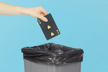 Throwing black playing card hearts 3 into the trash can, outstretched hand with playing card in front of trash can