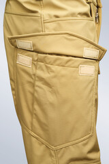 A detailed view of a khaki-colored pants pocket showcasing intricate stitching and closure design,...