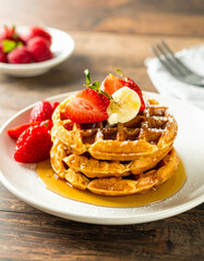 A stack of waffles with strawberries and whipped cream on top
