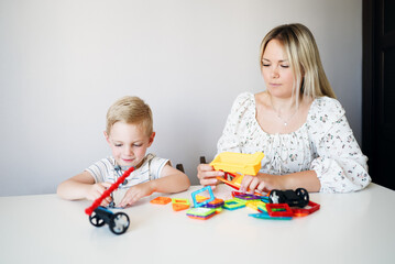 A young boy builds a magnetic STEM construction toy at home, developing problem-solving abilities, creativity and fine motor skills through hands-on educational play.