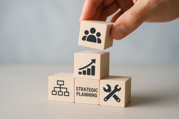 Hand stacking wooden blocks with icons representing teamwork, growth, and strategy. Concept of strategic planning, organizational development, and teamwork dynamics in business.