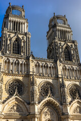 Naklejka premium Low angle view of the Gothic facade of Sainte Croix Cathedral in Orleans against a blue sky on a sunny day. Historical French religious architecture with intricate stone carvings and towers.