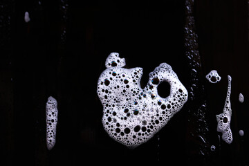 Curious bubbles form the outline of a face against a black background, creating a visually intriguing and abstract scene. The contrast highlights the bubbles' playful shapes.