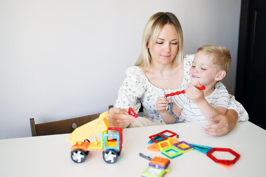 A young boy builds a magnetic STEM construction toy at home, developing problem-solving abilities, creativity and fine motor skills through hands-on educational play. - Powered by Adobe