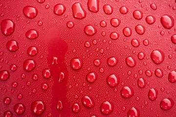 Bright red surface adorned with water droplets, showcasing natures beauty in simple yet captivating detail