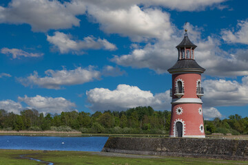 Historical Moritzburg Lighthouse on the Castle Pond under a dramatic blue sky with white clouds. Red facade and dark roof building