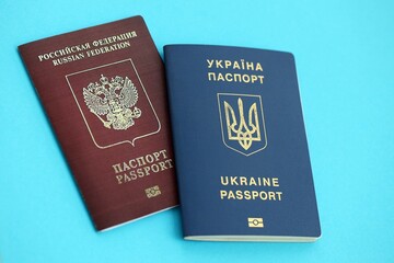 Ukraine and Russian Federation passports on light blue table background close up. Concept of restrictions and sanctions during war in Ukraine