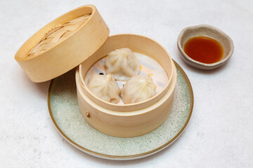 Xiao Long Bao au poulet – brioche de Shanghai servie dans un panier à vapeur avec sauce
