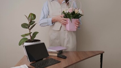 Female office worker in stylish beige and blue suit taking flowers from desk for International Womens Day celebration, tablet with chroma key.