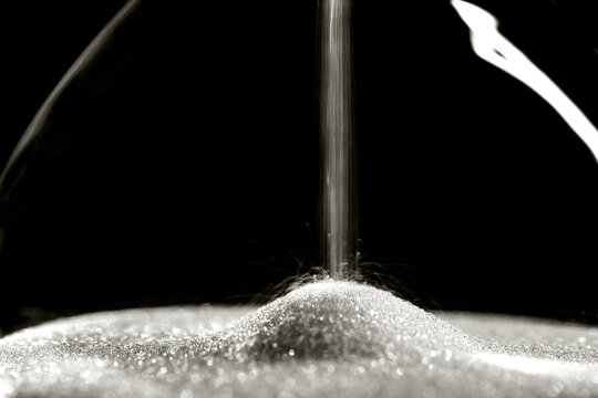 Sparkly hourglass sand on black background. Minimalist low key photo for concepts of time, travel to the desert color of 2026 year cloud white