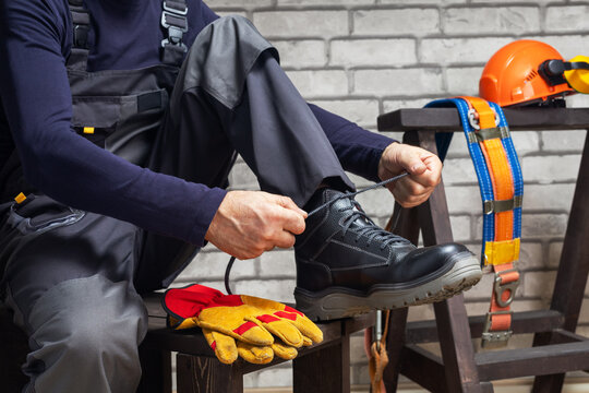 Construction worker putting protective boots, yellow gloves and hard hat.