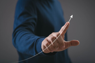 A person drawing an upward glowing curve with a fingertip, symbolizing business growth, increasing performance, positive trend, financial success, and modern data-driven progress concepts.