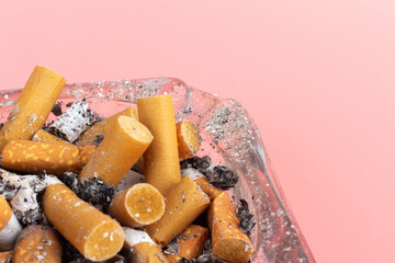 Fototapeta premium cigarette butts torn on pink background ashtray