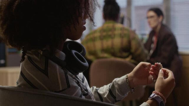 Focus on stressed female multiethnic teenager waiting while her mother talking to female school counselor and principal in office