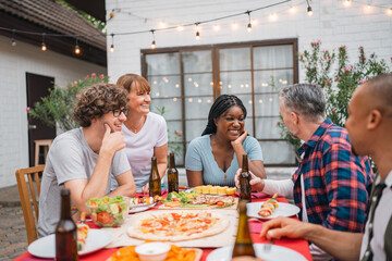 Festive Christmas celebration with family and friends gathered around a joyful holiday feast, wearing Santa hats, enjoying delicious food, desserts, and sparklers in a cozy and decorated home