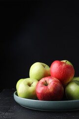 Fresh red and green apples on dark textured table against black background. Space for text