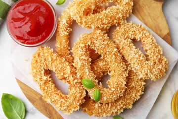Deep fried squid rings, basil and ketchup on light table, flat lay