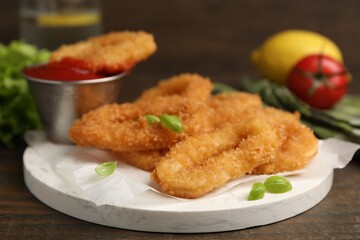 Deep fried squid rings with basil and ketchup on wooden table, closeup