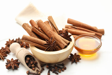 Different spices (anise, cinnamon, cloves) and honey for mulled wine on white table