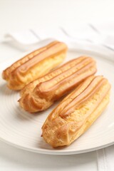Fresh tasty eclairs on white table, closeup
