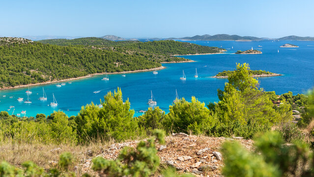 Croatian coastal landscape with small islands in the sea, green forest and blue water, view from a hill on a natural landscape on a sunny day.