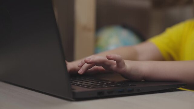 children hands typing keyboard. close-up. boy studying remotely at home. kid classes school computer class. child son writes with keys while working computer. children time to learn getting knowledge.