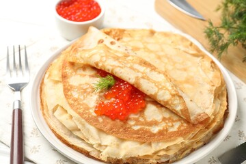 Tasty crepes with red caviar and dill on table, closeup