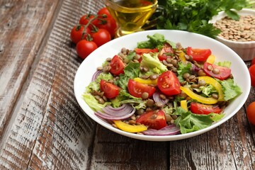 Delicious lentil salad and ingredients on wooden table, closeup. Space for text