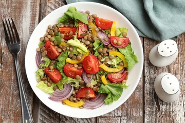 Delicious salad with lentils and vegetables served on wooden table, flat lay