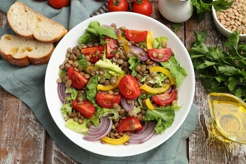 Delicious lentil salad and ingredients on wooden table, flat lay