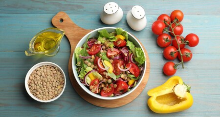 Delicious lentil salad and ingredients on light blue wooden table, flat lay