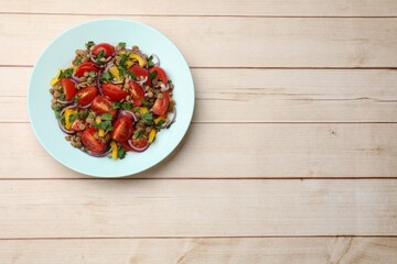 Delicious salad with lentils and vegetables on light wooden table, top view. Space for text
