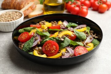 Tasty salad with lentils and vegetables on grey table, closeup