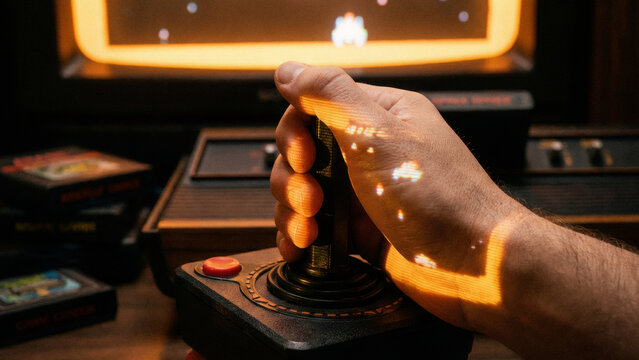 Man playing retro video game on old console. Player holding vintage joystick. Nostalgic arcade game projection on hand. Entertainment concept for past times.