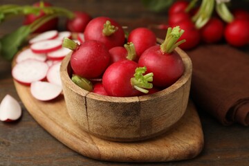 Fresh radishes in bowl on wooden table, closeup