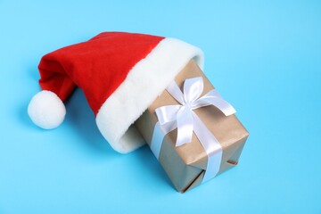 Santa hat and Christmas gift on light blue background, above view