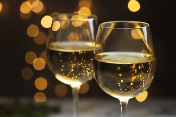 Glasses of white wine against blurred lights, closeup. Christmas and New Year celebration