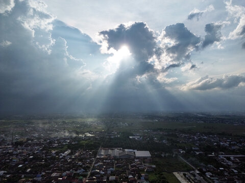 A dramatic sky with sun rays breaking through dark clouds over a wide landscape