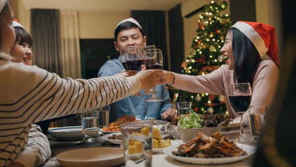 Group of Asia colleague friends gathering New year holidays party together. Happy man host toast glass of wine with guest start eat christmas dinner at home in evening, celebration and people concept.