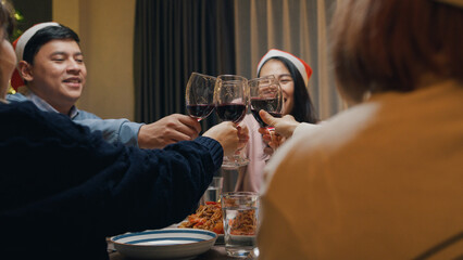 Group of Asia colleague friends gathering New year holidays party together. Happy man host toast glass of wine with guest start eat christmas dinner at home in evening, celebration and people concept.