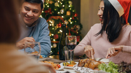 Group of Asia colleague gathering New year holidays party together. Group of happy friends enjoy eat good food over Christmas table thanksgiving dinner at home at night, celebrate and people concept.