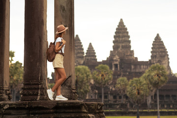 Naklejka premium Female Tourist Exploring Ancient Temple Angkor Wat in Cambodia at Sunrise