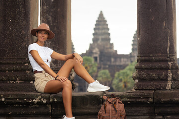 Fototapeta premium Angkor Wat Columns With Female Traveler Sitting, Cambodia Tourism Concept