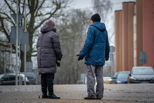 Elderly Couple Standing and Talking on a Quiet Winter City Sidewalk with Cane Support