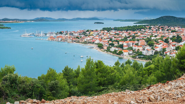 The coastal town of Pirovac in Croatia, with a panoramic view of the town, bay, and surrounding islands from Makirina Peak. Rain clouds and heavy rain pass over the islands.