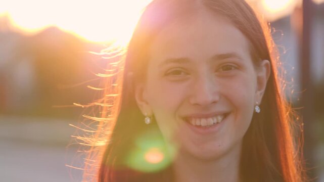 Young happy girl walks down the street smiling at sunset in the city, be satisfied with life, free woman walks in the park, walking, slow motion, student goes to study at dawn at the institute.