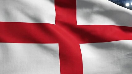 An English flag waves in front of a stadium with bright lights