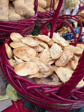 Traditional smoked Tatra sheep cheese oscypek displayed in a basket at a holiday market. Authentic regional delicacy with carved patterns.