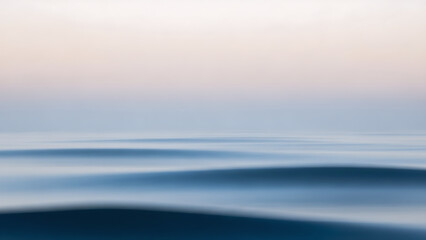 Obraz premium Abstract, minimalist long exposure of calm ocean waves at sunset. Soft pastel colors and blurred motion create a serene, dreamy, and tranquil seascape, ideal for backgrounds and design.