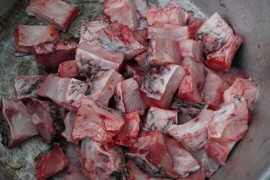 Raw chopped rohu fish pieces in a metal bowl ready for cooking